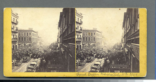 Unnumbered View - Grand Organ Wager Sept 11, 1867 - (handwritten on back) Sept 11, 1867 A.N(.?) Higgins marched along Montgomery playing hand organ to fulfill wager on election; Jones Sample Rooms, California & Montgom